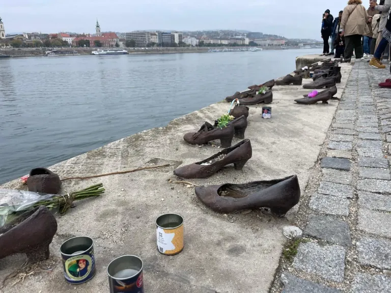 Eiserne Schuhe des Mahnmals Schuhe am Donauufer in Budapest, dazwischen Gedenkkerzen und Blumen,